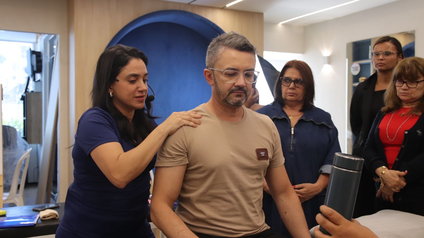 Elayne Vieira corrigindo postura de aluno durante a prática